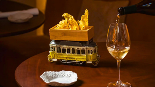 Creative dish served in tram model with wine being poured into glass.