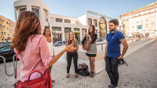 Group of five people talking outside a modern building on a sunny day.