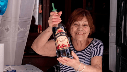 Smiling woman holding a bottle of wine indoors.