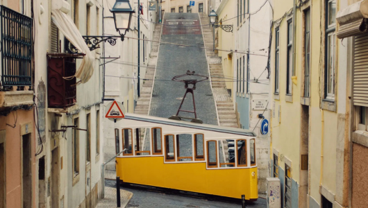 Yellow tram on a steep, narrow street with old buildings.