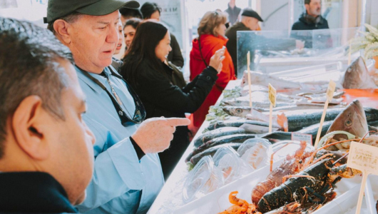 People selecting seafood at a market counter.