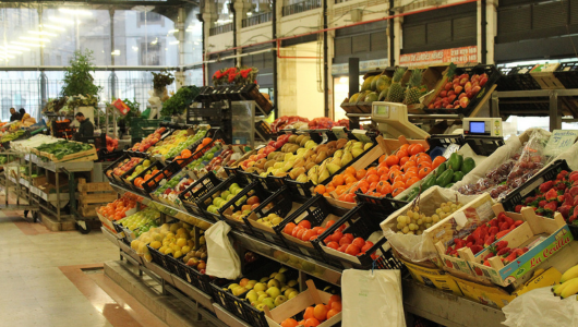 Indoor market with various fruits and vegetables on display.