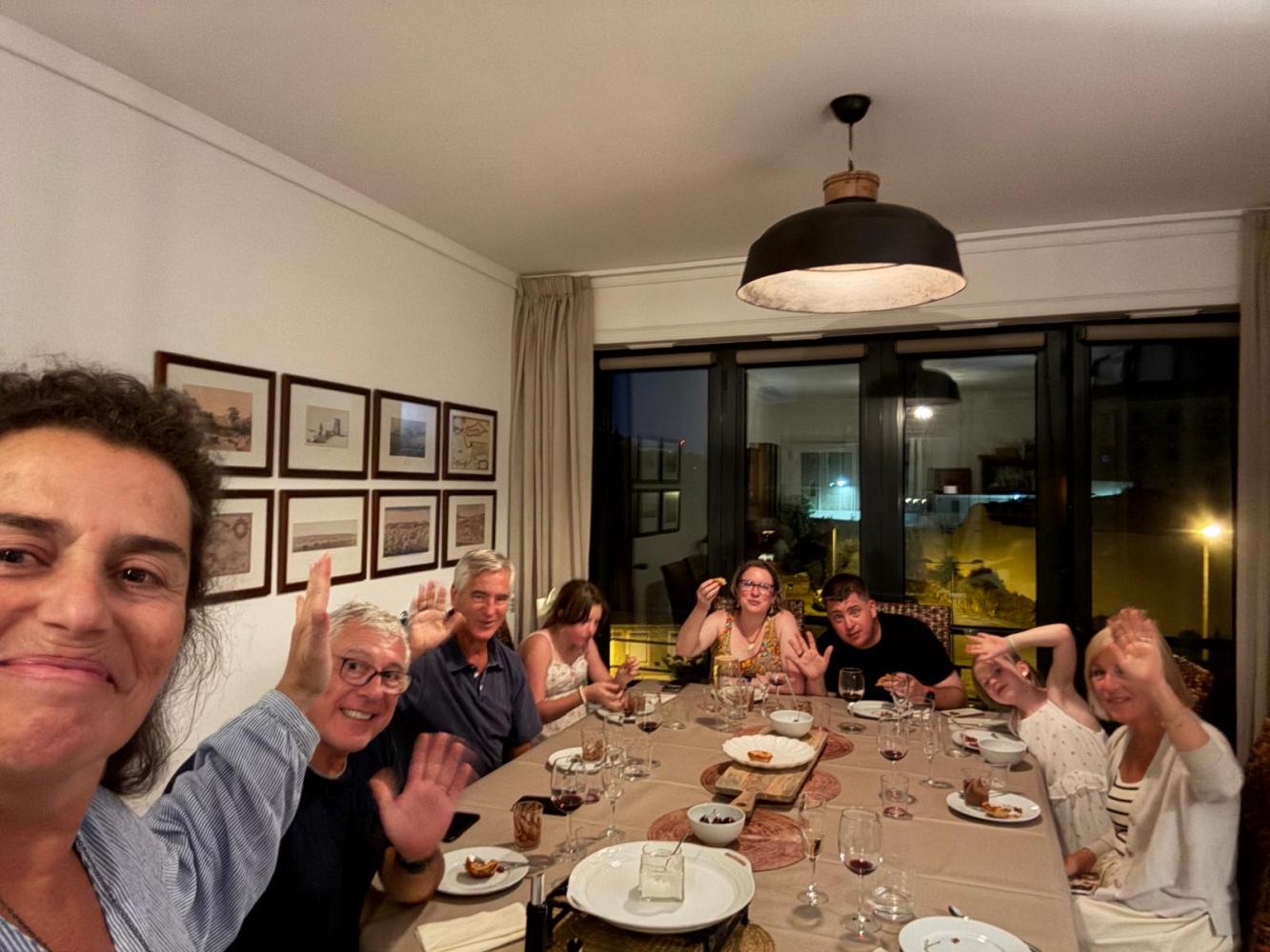Group of people at a dining table waving and smiling.