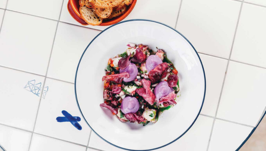 Salad with greens and radicchio in white bowl, sliced bread beside.