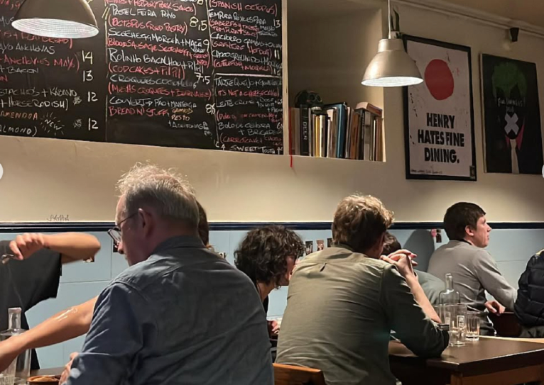People seated in a cafe with menu boards and wall posters visible.
