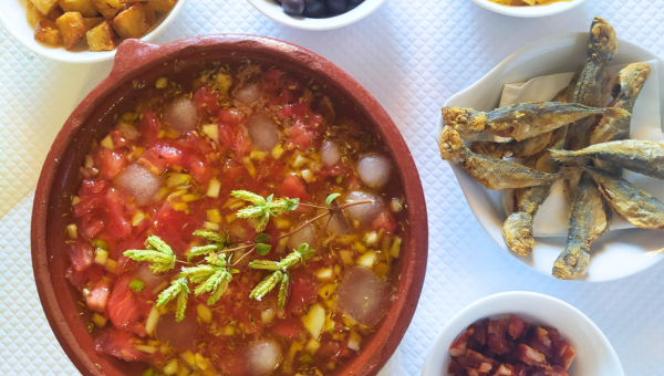 Bowl of soup with toppings, herbs, and several small dishes on the side.