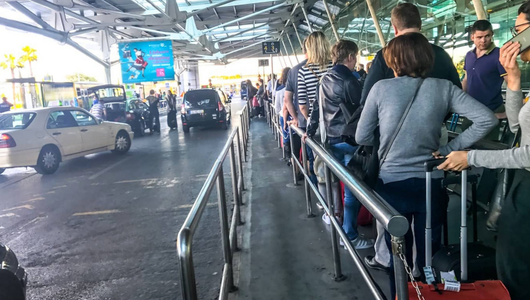 People with luggage in line at airport taxi stand.