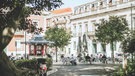 Outdoor cafe with people sitting under trees in a European square.