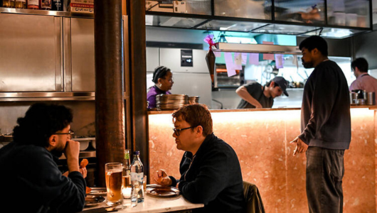 People dining in a restaurant with chefs cooking in the background.