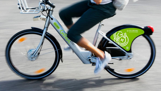 Person riding a green and white bicycle on pavement.