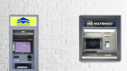 Two ATMs, Euronet and Multibanco, on a white brick wall.
