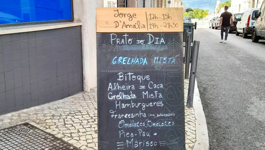 Outdoor menu board listing Portuguese dishes and hours.