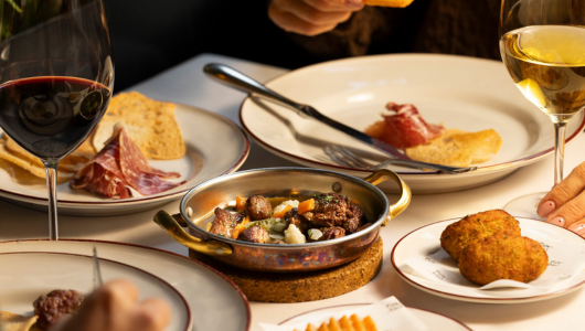 Assorted dishes with wine, including meat, bread, and appetizers on a dining table.