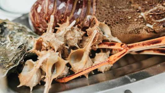 Assorted seafood on a tray, including a lobster, shells, and crustacean claws.
