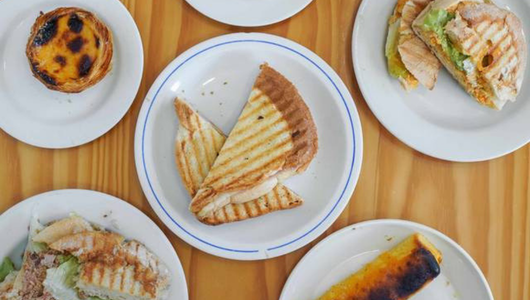Assorted sandwiches and pastries on white plates.