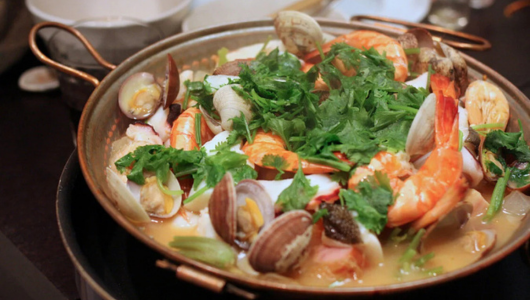 Seafood stew with shrimp, clams, and herbs in a large pot.