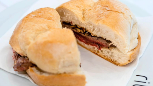 Sandwich with beef slices on white napkin.