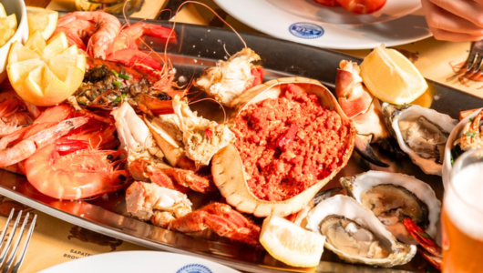 Seafood platter with oysters, prawns, crab, and lemon wedges.