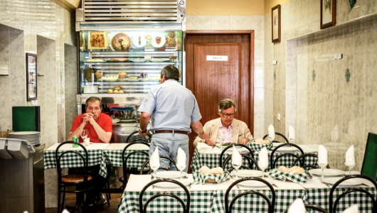 Diners at tables with green checkered tablecloths in a cozy restaurant.