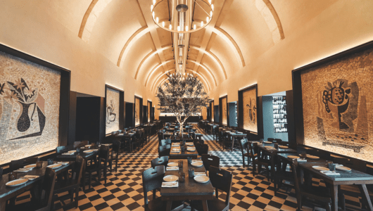 Elegant restaurant with arched ceiling, wall art, and centered tree.