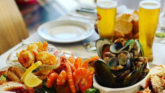Seafood platter with mussels, shrimp, and beer on a table.
