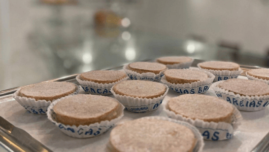 Tray of round pastries in paper cups on display.