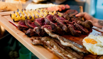 Wooden board with sliced steak, grilled pineapple, and a fried egg.