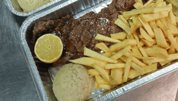 Tray with steak, fries, rice, and half a lemon on the side.