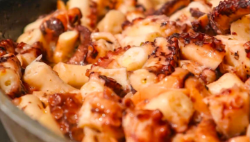 Close-up of cooked octopus pieces in a pan.