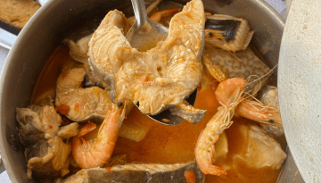 Seafood stew with fish, shrimp, and vegetables in a pot.