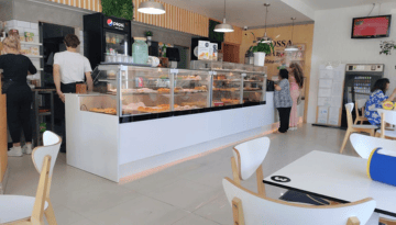 People inside a cafe with display cases of pastries and a seating area.