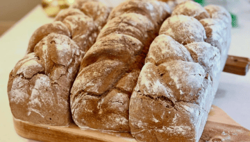 Three loaves of braided bread on a wooden board.
