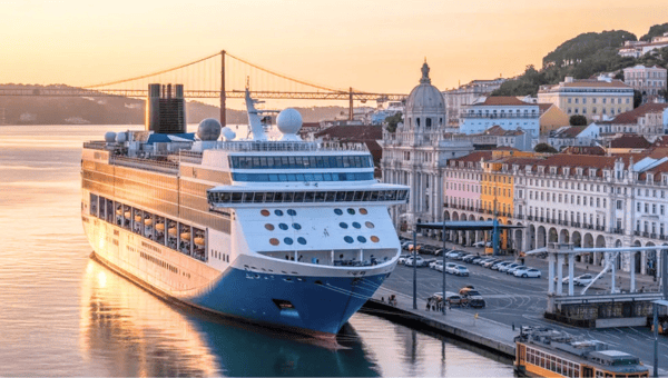 Cruise ship docked in a scenic city harbor at sunset.