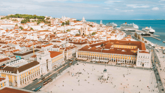 Aerial view of a city square with historic buildings and nearby cruise ships.