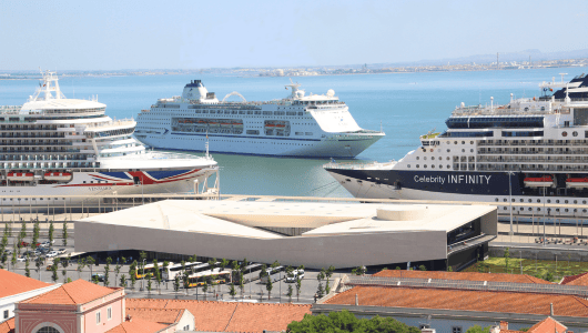 Three cruise ships docked at a harbor under clear blue skies.