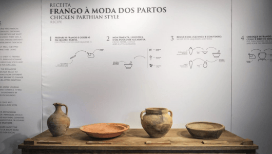 Ancient pottery on a wooden table with a recipe text on the wall behind.