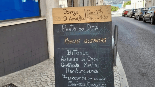 Chalkboard menu outside cafe on street with cobblestones.