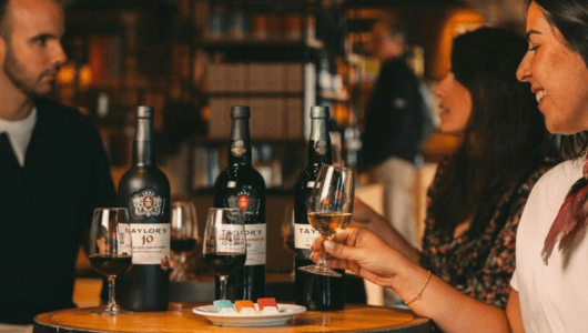 People enjoying wine at a table with bottles and glasses.