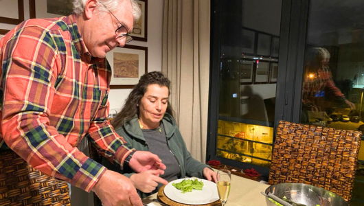 Man serving salad to woman seated at a dining table indoors.