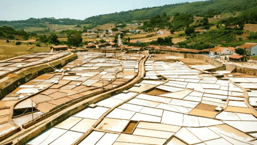 Aerial view of salt pans with surrounding countryside and buildings.