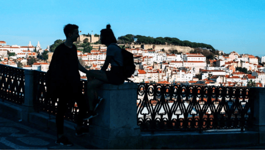 Silhouetted couple overlooking cityscape with historical buildings.