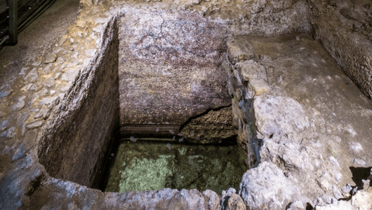 Ancient stone well with visible water at the bottom.