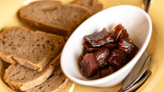 Sliced bread and a bowl of diced meat on a plate.