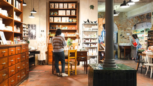 Cozy store interior with wooden shelves, a person browsing, and various products on display.