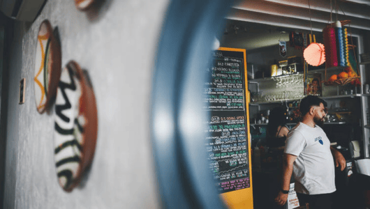 Blurred man in a cafe, wall plates in focus, colorful decor.